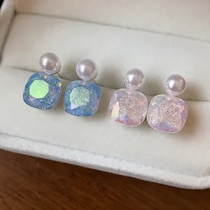 Close-up of geometric aurora texture pearl earrings in blue and pink in a velvet box