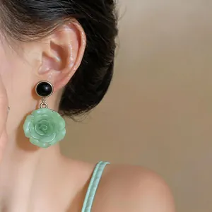 Elegant light green resin rose pendant earrings with black round studs shown on model