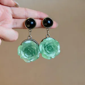 Detail view of elegant green resin rose pendant earrings with black studs.