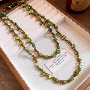 Elegant bohemian green shell beaded necklace with amber crystal accents in a jewelry tray