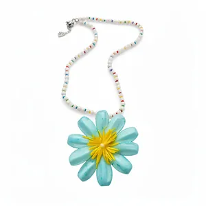 Bohemian style beaded necklace with large blue flower pendant on white background