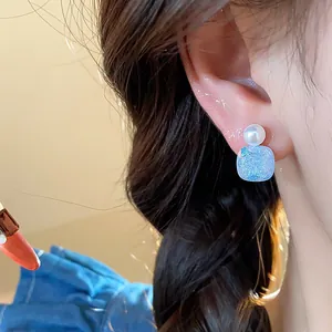 Detailed view of elegant silver needle geometric pearl stud earrings worn on ear