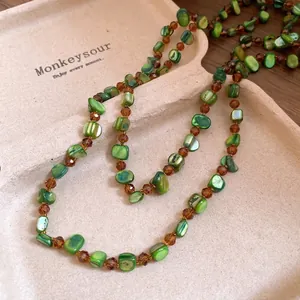 Bohemian style long necklace featuring green shell beads and amber crystal accents