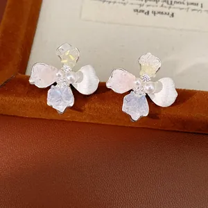 Dettaglio ravvicinato di orecchini a fiore con cristalli e perle su pelle chic