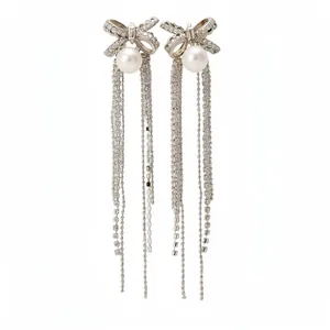 Elegant silver bow earrings with pearls and long glittering tassels on white background