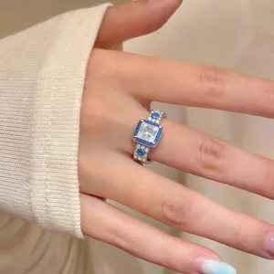 Dettaglio di un anello in argento con zircone blu quadrato sul dito di una donna moderna