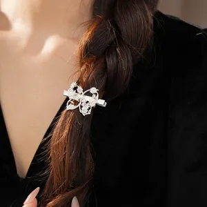 Elegant zircon butterfly and flower hair clip detail on dark braided hair background