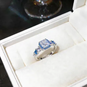 Dettaglio di un elegante anello in argento con zirconi quadrati in blu e bianco lucido.