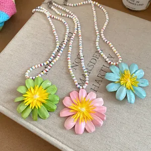Detailed macro shot of three colorful daisy flower beaded necklaces on a book cover