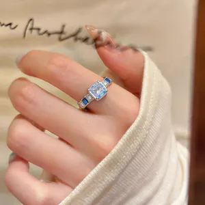 Dettaglio di un anello aperto in argento con zirconi quadrati blu e trasparenti