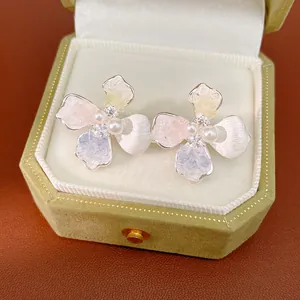 Primo piano di eleganti orecchini a fiore con perle e zirconi in una confezione regalo
