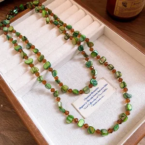 Close-up of bohemian green shell and amber beaded necklace in jewelry tray