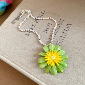 Close-up of vibrant green and yellow flower pendant on a colorful pearl beaded necklace