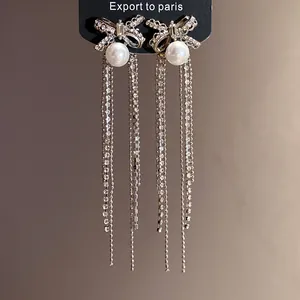 Close-up of bowknot tassel earrings with pearls and shimmering rhinestones