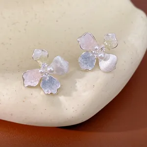 Dettaglio macro di orecchini a lobo a fiore dolce con perle e zirconi colorati