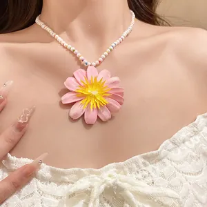 Close-up detail of a sweet pink flower pendant necklace with pearl beads on a model