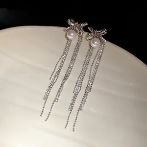 Elegant detail of silver bowknot tassel earrings featuring shimmering pearls and rhinestones