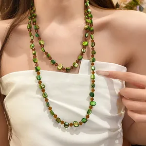 Detailed view of a Bohemian green shell beaded long necklace worn by a female model