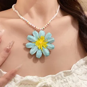 Detailed close-up showing a large light blue daisy flower pendant on a white beaded chain