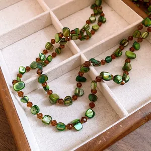 Detailed macro view of green shell and amber faceted beads on a bohemian necklace.