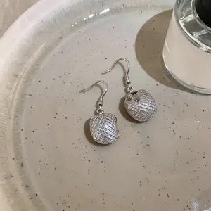 Primo piano di orecchini a rete d'argento su un vassoio di ceramica