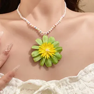 Detail of green flower pendant necklace with white pearl beads on neck.