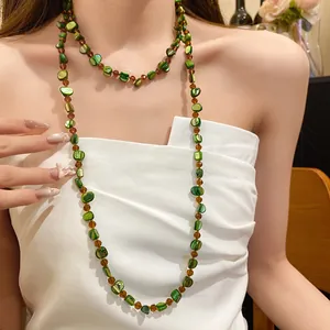Close-up detail of a bohemian green shell beaded necklace styled on a white strapless dress