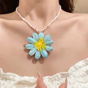 Detailed view of the light blue flower pendant on a multi-colored pearl beaded necklace