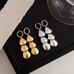 Close-up of elegant gold and silver tiered teardrop earrings on a velvet jewelry tray