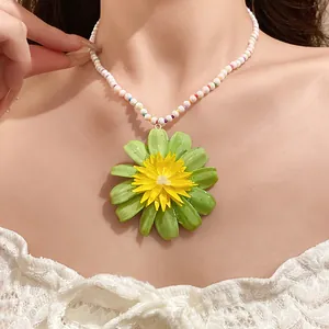 Close-up of a vibrant green and yellow flower pendant on a pearl beaded necklace