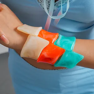 Detailed view of vibrant marbled resin irregular geometric bangles worn on the forearm