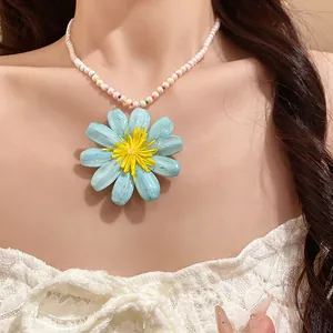Detailed close-up of a sweet blue daisy flower pendant on a white pearl beaded necklace