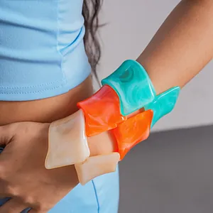 Close-up of colorful irregular resin bangles in dopamine style on a model's arm