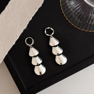 Detailed macro view of silver metallic tiered petal earrings featuring a polished smooth finish