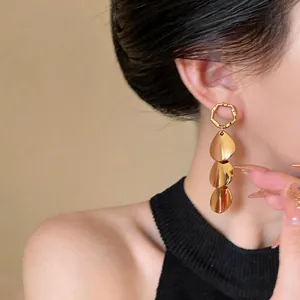 Close-up detail of modern gold geometric drop earrings with triple teardrop charms