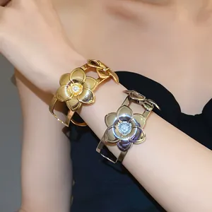 Nahaufnahme goldener und silberner floraler Armreifen mit Perlen auf dem Arm des Modells