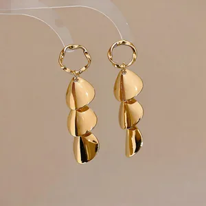 Detailed macro view of elegant tiered gold petal-drop metallic finish earrings.