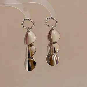 Close-up view of silver minimalist metallic drop earrings with layered petal design