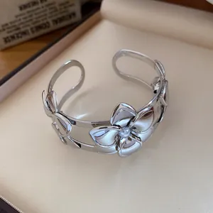 Nahaufnahme eines silbernen Blumen-Armreifs mit Perlen und doppellagigem Design.