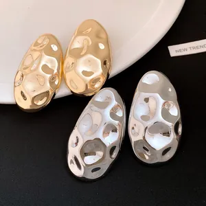 Close-up of gold and silver hammered oval stud earrings with retro metallic texture.