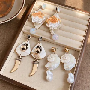 Elegant beach-inspired shell and pearl drop earrings displayed in a luxury jewelry tray