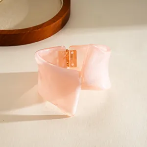 Close-up detail of a marbled pink resin bangle with a unique geometric twisted design
