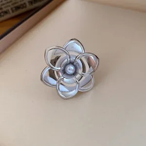 Detailansicht eines silberfarbenen zweilagigen Blumenrings mit Perle in der Mitte.