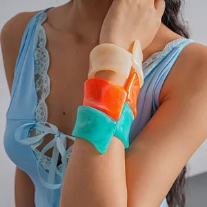 Detail of marbled resin bangles in vibrant orange, cream and turquoise on model's wrist.