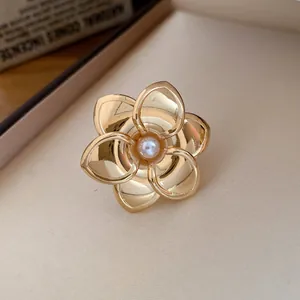 Exquisite Nahaufnahme eines goldenen Metallblumenrings mit einer zentralen weißen Perle