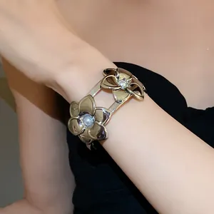 Detailansicht eines eleganten Metall-Armreifs mit doppelten Blumen und Perlen