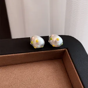 Dettaglio di orecchini a lobo ovali in argento opaco con pois in smalto colorato