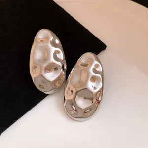 Close-up macro shot of silver oval stud earrings with a vintage hammered metal texture.