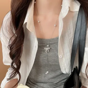 Detailed view of a long French style Y-shaped necklace with pearls and a bow pendant.