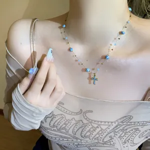 Macro detail view of a vintage style blue beaded necklace with gold cross pendant